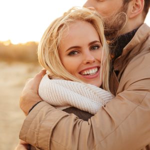 Close up portrait of a beautiful couple in love hugging while walking along the beach